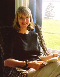 A woman sitting in a wicker chair reading a book.