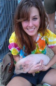 A young woman holding a pig at a fair.