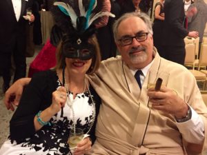 A man and woman wearing a masquerade mask.