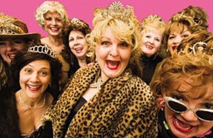 A group of women dressed in leopard coats and tiaras.