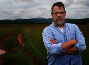 A man standing in a field with his arms crossed.