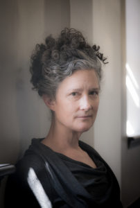 A woman with curly hair is looking at the camera.