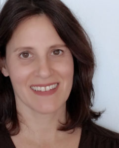 A woman in a brown shirt smiling for the camera.