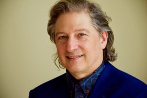 A man in a blue suit smiling for the camera.