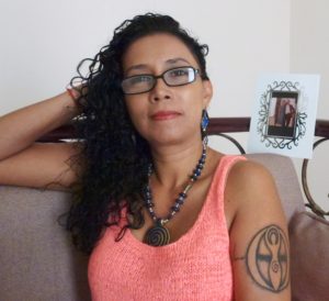A woman with glasses and tattoos sitting on a couch.