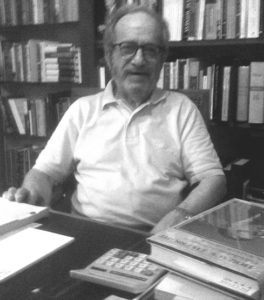 A black and white photo of a man sitting at a desk.