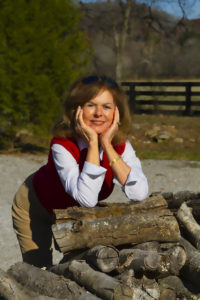 A woman leaning against a pile of logs.