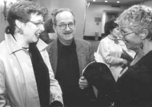 Three people talking to each other in a black and white photo.