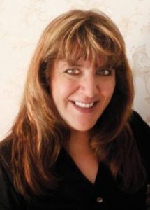 A woman with long brown hair smiling for the camera.