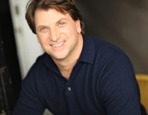 A man smiling in a blue shirt.